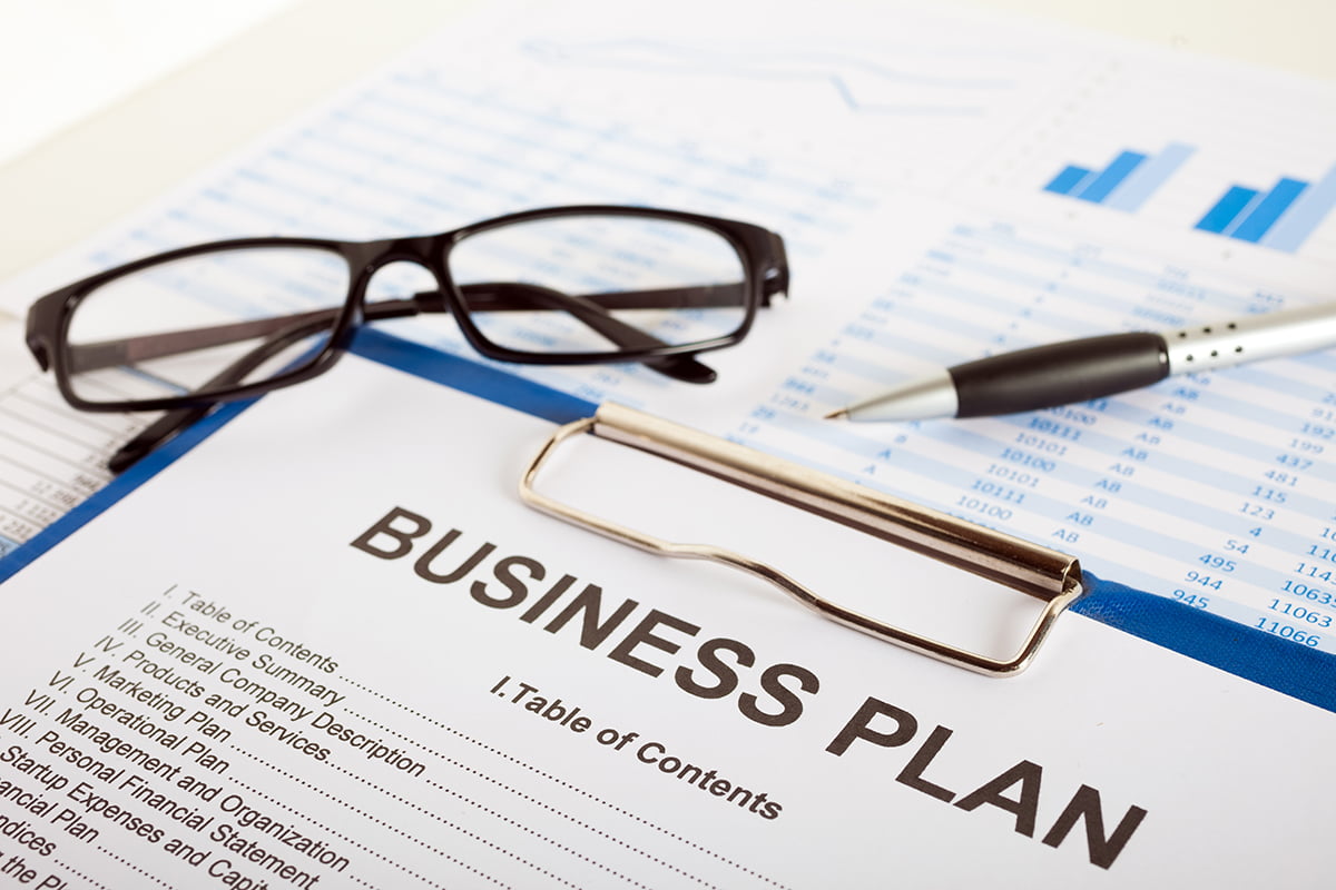 Business Plan paperwork on a desk with glasses and a pen